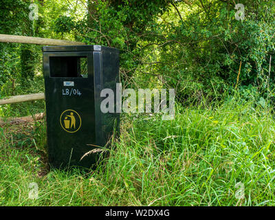 Green metal dustbin provided by the council next to a public footpath in woodland to encourage people not to drop litter Stock Photo