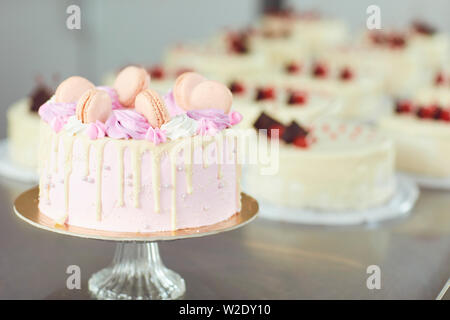 Beautiful pink cake decorated with macaroons on the table. Stock Photo