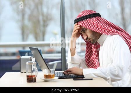 Confused arab man checking laptop content sitting in a coffee shop Stock Photo
