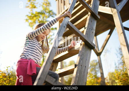 Young girl having fun at observation tower on Tauciuliskes cognitive walking way, leading through beautiful autumn forest to the Tauciliuskes lake, lo Stock Photo