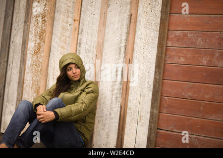 Young woman sitting against a wall Stock Photo