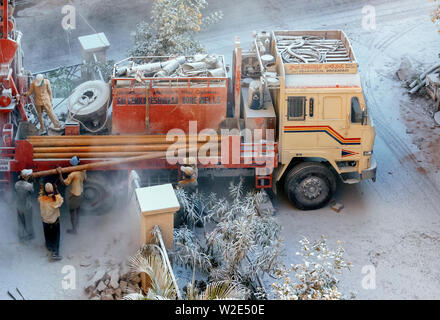 Workers loading/unloading metal pipes to/from a mobile drilling rig, drilling to locate ground water in Hyderabad, India. Stock Photo