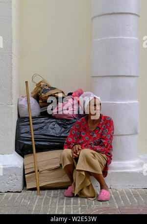 santo domingo, dominican republic - november 01, 2013: an old woman sitting on the roadside of calle el conde Stock Photo