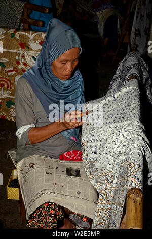 yogyakarta, di yogyakarta/indonesia - november 10, 2015: a woman applying wax patterns on textile fabrics in a batik factory Stock Photo
