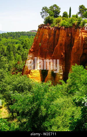 Intensive red cliff in the canyon landscape around village of Roussillon, Provence, France. Stock Photo