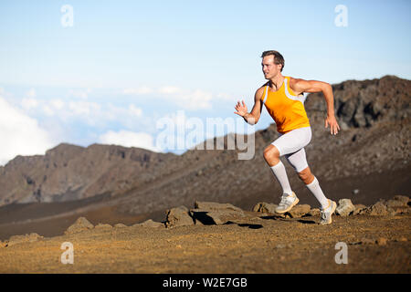 Running sport runner man sprinting in trail run. Fit male fitness sports athlete training sprint in amazing outdoor trail on volcano. Strength and success concept in compression shorts. Full body. Stock Photo