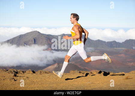 Runner man athlete running sprinting fast. Male sport fitness model training a sprint in amazing nature landscape outdoors at speed wearing sporty runners clothing compression shorts. Strong fit man Stock Photo