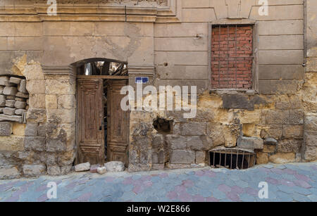 Grunge stone bricks wall with Broken wooden door and closed broken window in abandoned Darb El Labana district, Cairo, Egypt Stock Photo