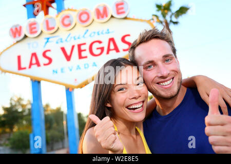 Las vegas couple happy and excited at welcome to fabulous Las Vegas sign billboard at the strip. Young multiracial people Asian woman and Caucasian man having fun on travel in Las Vegas Nevada USA. Stock Photo