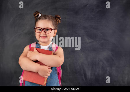 Little cute child holding books on blackboard.Education concept Stock Photo