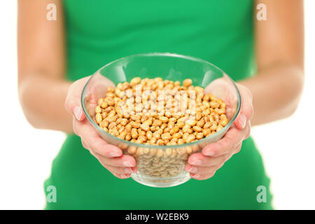 Dried salty soybeans - healthy snack. Woman showing asian snack: dry soya beans isolated on white background in studio. Stock Photo