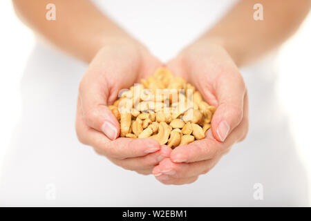 Cashew nuts - woman showing salty cashew nuts handful. Healthy food snack and ingredient shot in studio with shallow depth of field. Stock Photo