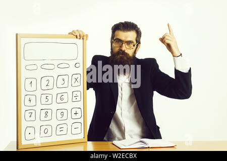 young handsome bearded man scientist or professor in teacher glasses with long beard holding board with calculator and book or notepaper sitting at ta Stock Photo