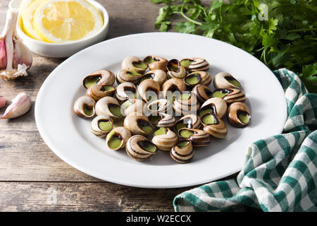 Escargots de Bourgogne on a plate isolated on wooden table Stock Photo