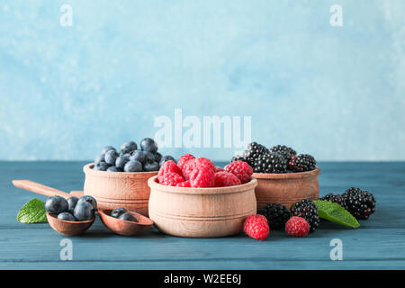 Small wooden bowls with berries on wooden table, space for text Stock Photo