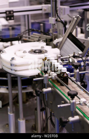 Small glass medicine bottles on a pharmaceutical packaging line. Selective focus. Stock Photo