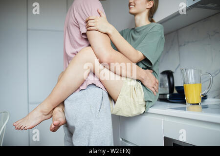 Happy young amorous couple in embrace enjoying being together while staying at home on weekend Stock Photo