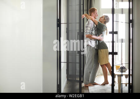 Young affectionate spouses looking at each other while embracing in the morning Stock Photo