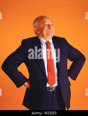 Middle-age man wearing a suit standing proud of his arms on his hips Stock Photo