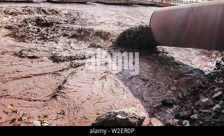 The industrial wastewater is discharged from the pipe into the water. Stock Photo