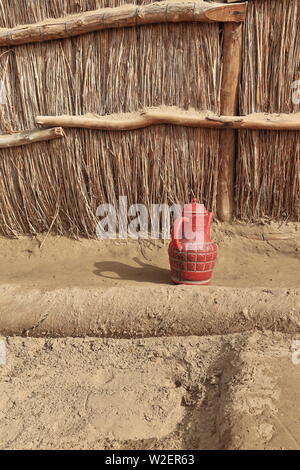 Red plastic pitcher-Uyghur reeds and mud hut yard. Taklamakan Desert-Xinjiang-China-0293 Stock Photo