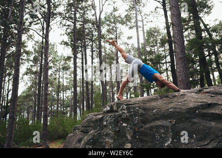 Man doing a downward facing dog pose in the woods Stock Photo