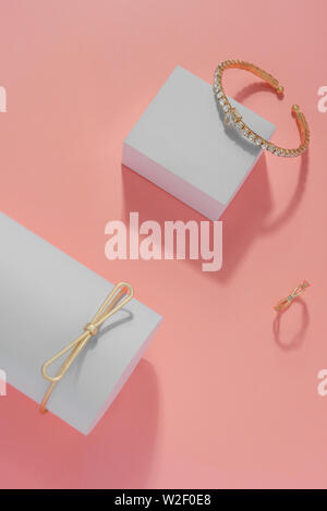 Vertical composition of Modern golden bracelets and ring on pink background top view Stock Photo
