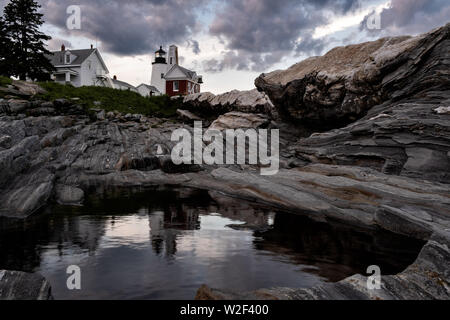 The historic Pemaquid Point Lighthouse reflected in a pool of water in the rocky landscape in Bristol, Maine. The picturesque lighthouse built along the rocky coast of Pemaquid Point was commissioned in 1827 by President John Quincy Adams. Stock Photo