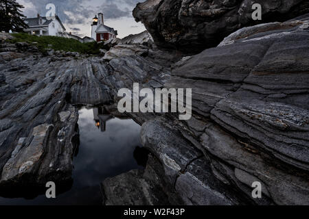 The historic Pemaquid Point Lighthouse reflected in a pool of water in the rocky landscape in Bristol, Maine. The picturesque lighthouse built along the rocky coast of Pemaquid Point was commissioned in 1827 by President John Quincy Adams. Stock Photo