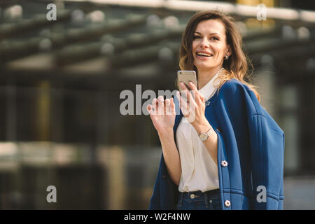 Office buildings city people in suit. Caucasian businesswoman using smartphone with hand. Business concept. Portrait stylish business woman in Stock Photo