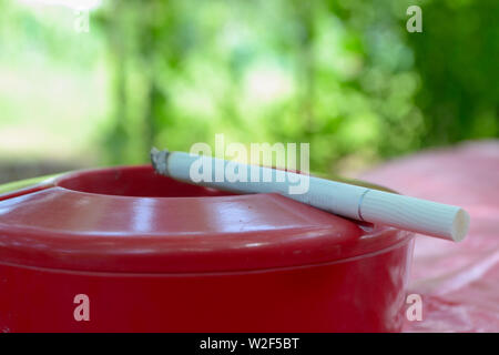 Burning cigarette in red ashtray Stock Photo