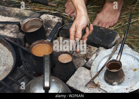Boiling coffee in turkish cezva on a grate over a burning bonfire, camping concept Stock Photo