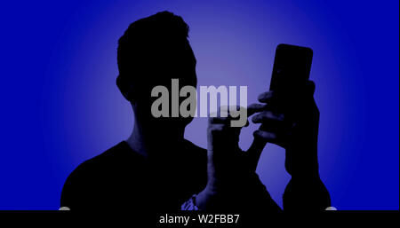 Silhouette of a male using his smartphone on a digital blue background Stock Photo
