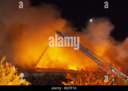 Modesto, CA, USA. 8th July, 2019. One of 5 ladder trucks from Modesto Fire and Ceres Fire Departments shoots water on the north end of the structure. Modesto Fire Department responded to a working structure fire at the corner of Tully Road and 9th Street Tuesday, July 7, 2019 at 9pm. The fire quickly went to multiple alarms bring 3 fire ladder truck along with multiple other engines from throughout Stanislaus County. Credit: Marty Bicek/ZUMA Wire/Alamy Live News Stock Photo