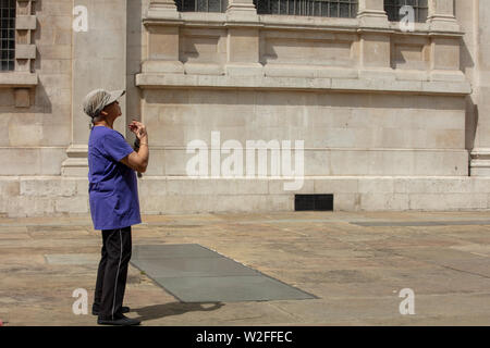 Mainly older people exercising the ancient Chinese slow moving exercise tai chi on the court behind the London church of St Martin in the Fields Stock Photo
