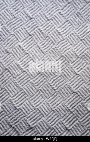 Woven cross-hatch pattern hand-raked into an abstract textured background in the monochrome white sand gravel of a Japanese Zen garden Stock Photo