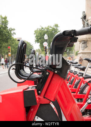 Row of red bicycles in a bike rack, available for rental on the streets of Barcelona Stock Photo