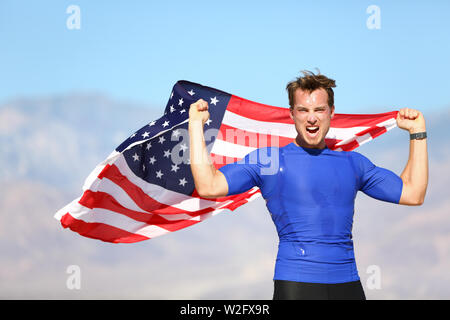 American success man athlete winning with USA flag celebrating victory. Fit male winner fitness model cheering in celebration of success win. Face expression with determination. Stock Photo