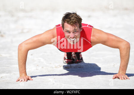 Push-ups - Fitness man crossfit training outdoors in desert showing power, strength and determination. Male athlete doing push up in extreme nature landscape. Stock Photo