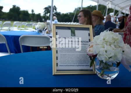 District Cup Polo match covered tent area with purpose of event sign and flower in clear vase on a table Stock Photo