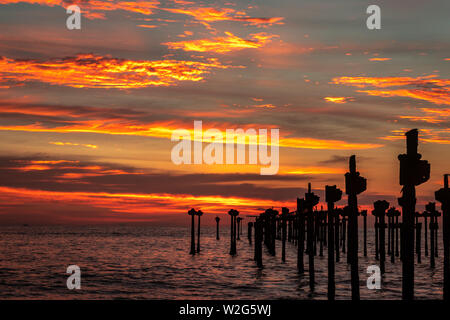 Orange cloud on sea horizon with leading iron poles towards the sun Stock Photo