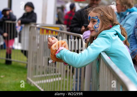 Meriden, CT USA. Apr 2019. Daffodil Festival. Young girl with face art about to flip a coin. Stock Photo