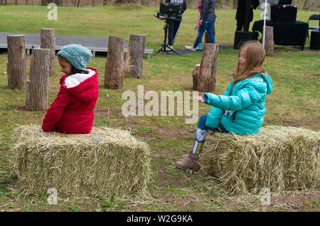 Meriden, CT USA. Apr 2019. Daffodil Festival. Young girls having simple fun with throwing hay at each other. Stock Photo