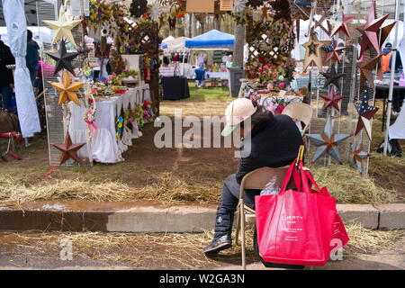 Meriden, CT USA. Apr 2019. Daffodil Festival. African American woman checking mud on her boots after a slight rainfall. Stock Photo