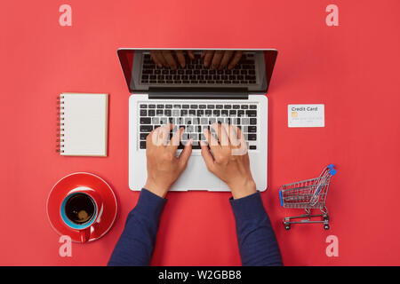 Man hand typing on laptop keyboard with blank screen monitor on red background Stock Photo