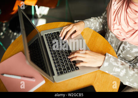Close-up image of young woman in hijab working on laptop when sitting at table in cafe Stock Photo