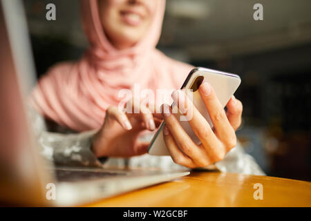 Manicured hands of woman in hijab sending text message Stock Photo