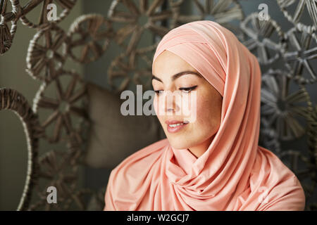 Beautiful contemplating young Muslim woman looking down and smiling Stock Photo