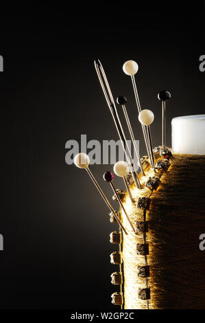 Threads with needles stuck into the bobbin on black background Stock Photo