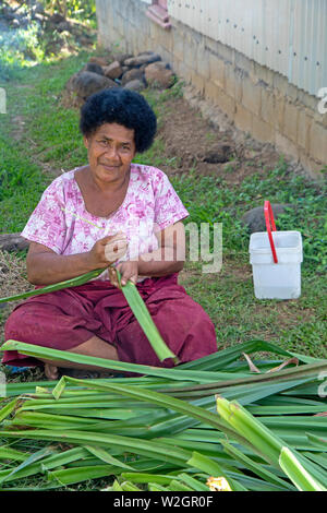 Woman prpearing pandanus leaves to weve into a mat in the highlands village of Navala Stock Photo